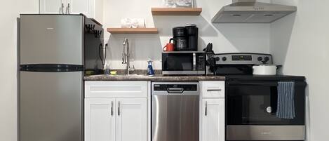 Une cuisine moderne dotée d’appareils électroménagers en acier inoxydable, de meubles blancs et d’un plan de travail en bois.