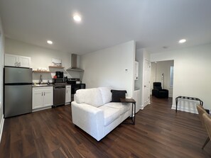 Un apartamento moderno con cocina, un sofá blanco, un comedor y una silla negra.