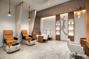 A modern spa room with massage chairs, a small table, and shelves with decorative items.