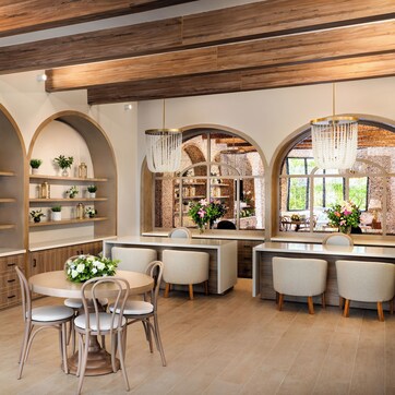A modern kitchen with wooden beams, arched shelving, and a central island with chairs.