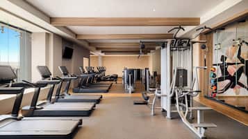 Academia moderna com esteiras, aparelhos de musculação e um espelho grande.