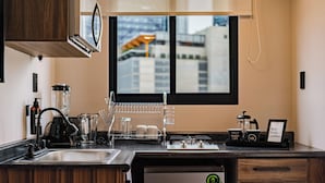 A modern kitchen with a dishwasher, coffee maker, and a window with a city view.