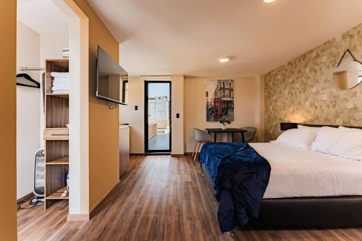 Une chambre d’hôtel comprenant un lit, un bureau, une chaise, une télévision et une armoire.