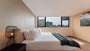 A modern bedroom with a large window, a bed with white linens, a black nightstand, and a unique wireframe lamp.
