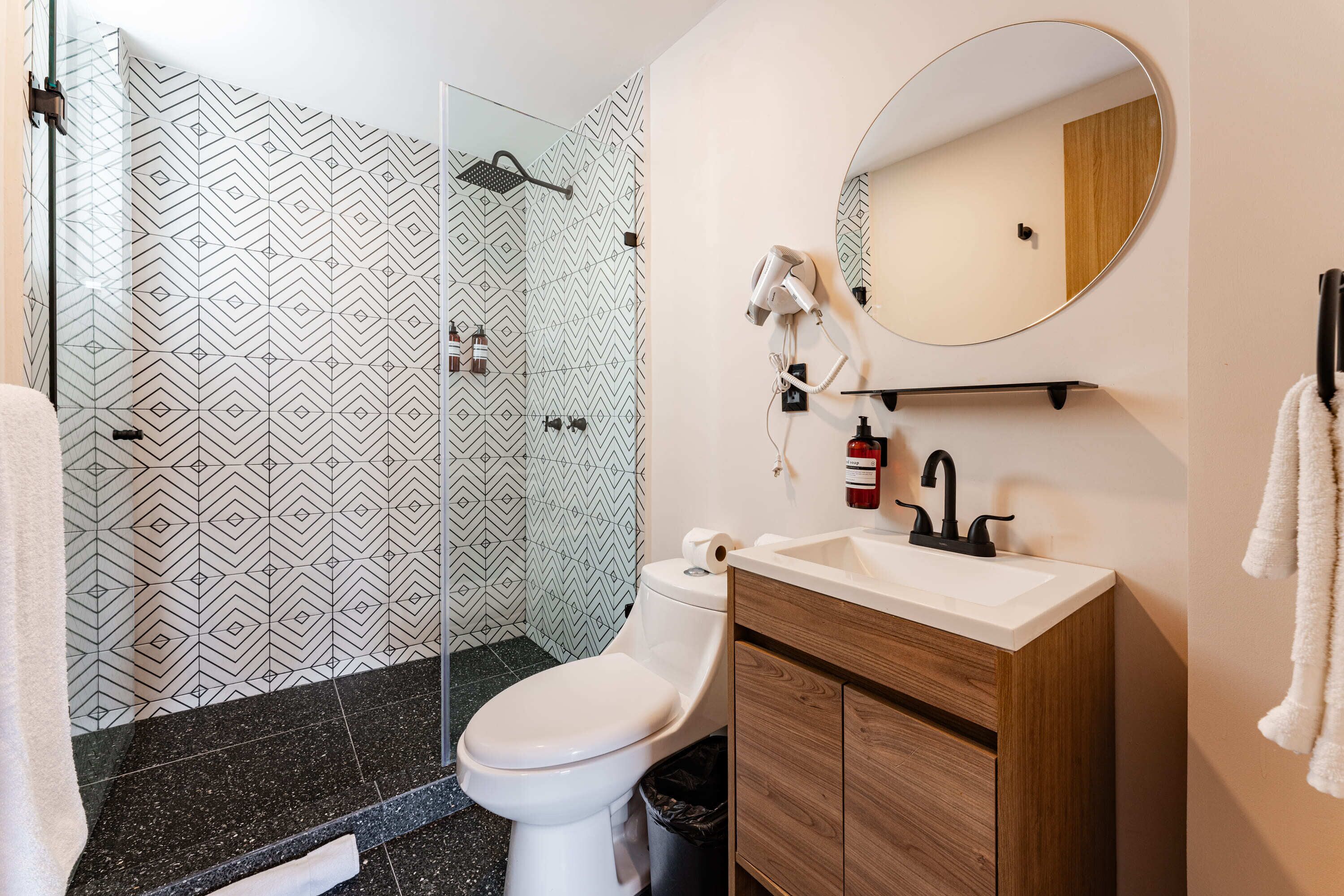 A modern bathroom with a shower, toilet, and vanity.