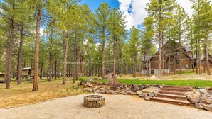 Una cabaña con un hogar de piedra y escalones de madera, rodeada de un área boscosa.