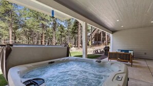 Un jacuzzi en un área exterior techada con vista a un bosque.