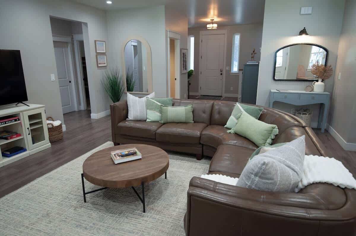 A modern living room with a brown leather sofa, a round coffee table, and a bookshelf.