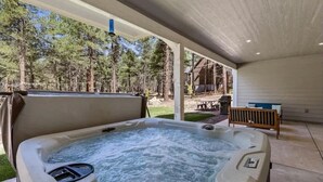Een hottub in een overdekte buitenruimte met uitzicht op een bos.