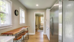 A kitchen with a wooden bar, stainless steel refrigerator, and a clock on the wall. - Charming Greensboro Home - 2 Mi to Downtown! (Greensboro)