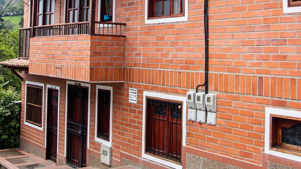 A red brick building with a balcony, a door, and a window. - Chali (Retiro)