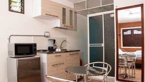 A compact kitchen with a microwave, coffee maker, and a small refrigerator. There is a dining area with a metal table and chairs. - Chali (Retiro)