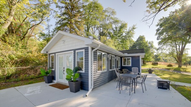 Ett hus med en täckt uteplats, en matplats med stolar och krukväxter.