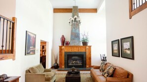 A living room with a fireplace, two sofas, a coffee table, and a chandelier. - Modern 2 bed / 2 bath condo with hot tub. 5 min to Skiing and Main St.! (Park City)