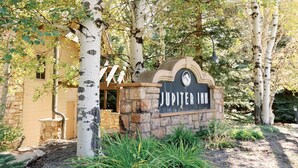 A sign for Jupiter Inn surrounded by birch trees and a stone wall. - Modern 2 bed / 2 bath condo with hot tub. 5 min to Skiing and Main St.! (Park City)