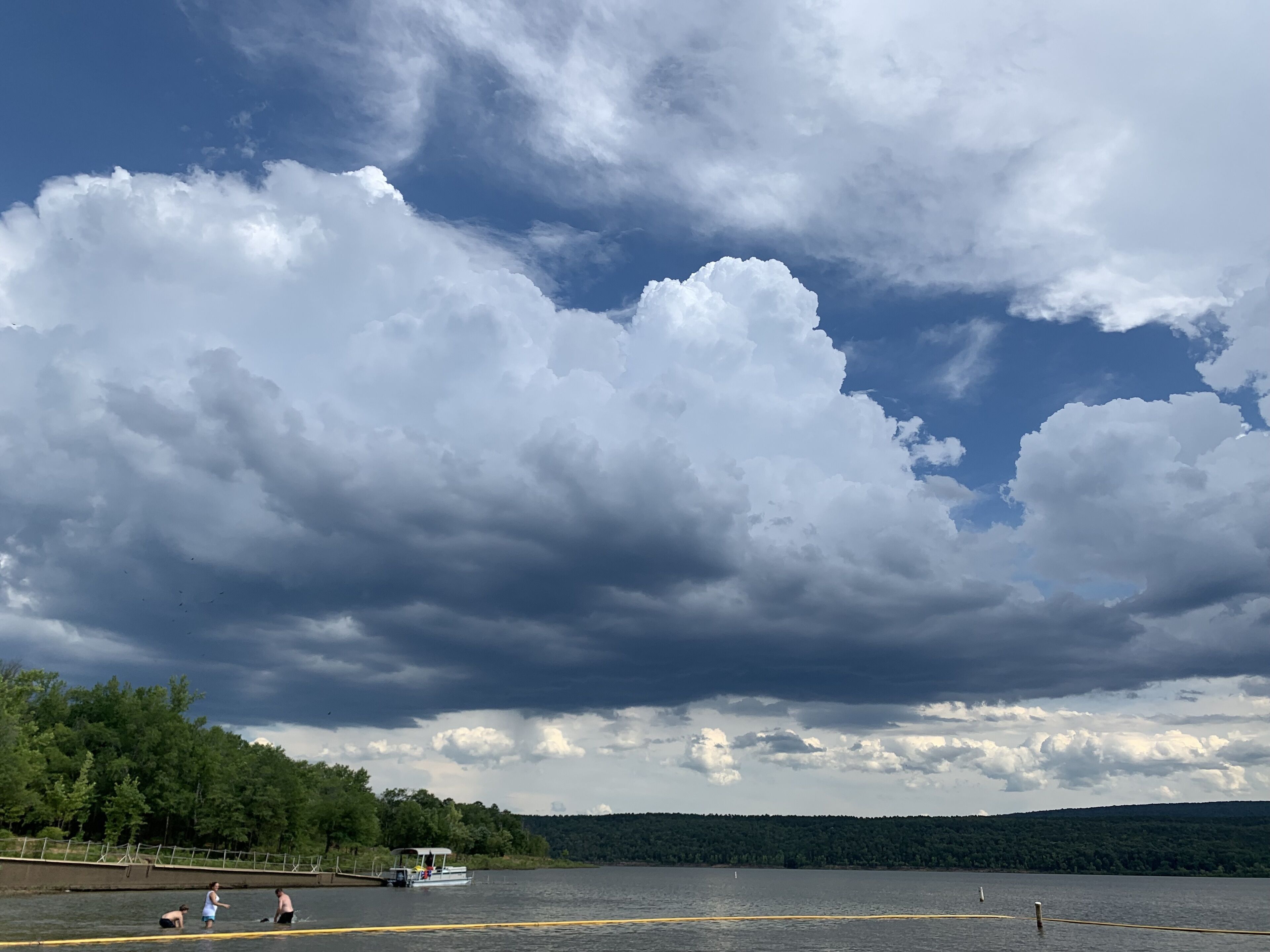 A lake with a dock and people near the water.