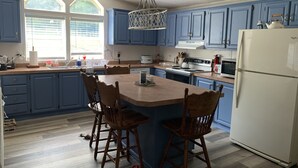 A kitchen with blue cabinets, a white refrigerator, and a wooden island with bar stools. - Davis Ranch in beautiful Plainview Arkansas next to Nimrod Lake. Pet Friendly. (Plainview)