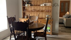A dining area with a wooden table and chairs, a chandelier, and a wooden cabinet with glassware. - Davis Ranch in beautiful Plainview Arkansas next to Nimrod Lake. Pet Friendly. (Plainview)