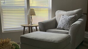 A living room with a grey sofa, a patterned pillow, a small table with a lamp, and a mug with text. - Davis Ranch in beautiful Plainview Arkansas next to Nimrod Lake. Pet Friendly. (Plainview)