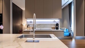 Cozinha moderna com bancada de mármore, pia de aço inoxidável e forno embutido.
