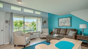 A spacious living room with a large sliding glass door leading to a balcony, a blue accent wall, and a ceiling with skylights. - Condo in Crescent Bar Resort—20 minutes from the Gorge amphitheater. (Quincy)