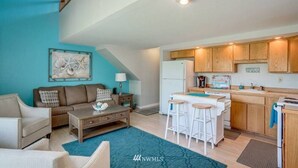 A modern kitchen with wooden cabinets, a white refrigerator, and a bar area with stools. - Condo in Crescent Bar Resort—20 minutes from the Gorge amphitheater. (Quincy)