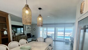 A modern kitchen with a marble countertop, wooden cabinets, and a view of the beach. - Renovated, direct oceanfront 5BR/6BA private pool home sleeps 16. (New Smyrna Beach)