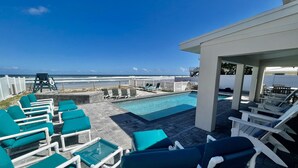 A poolside area with lounge chairs and a view of the ocean. - Renovated, direct oceanfront 5BR/6BA private pool home sleeps 16. (New Smyrna Beach)