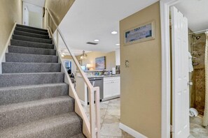 A staircase leading to a kitchen area with a view of the beach.