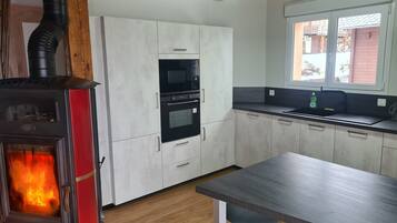 Una cocina moderna con estufa de leña, horno empotrado, microondas y ventana con vistas al exterior.