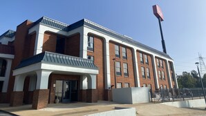 Een modern gebouw met een bakstenen gevel, grote ramen en een opvallende vlaggenmast.
