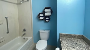 A bathroom with a bathtub, toilet, and a towel rack with towels. - HomeTowne Studios by Red Roof Prattville (Prattville)