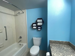 Een badkamer met een bad, toilet en een handdoekrek met handdoeken.