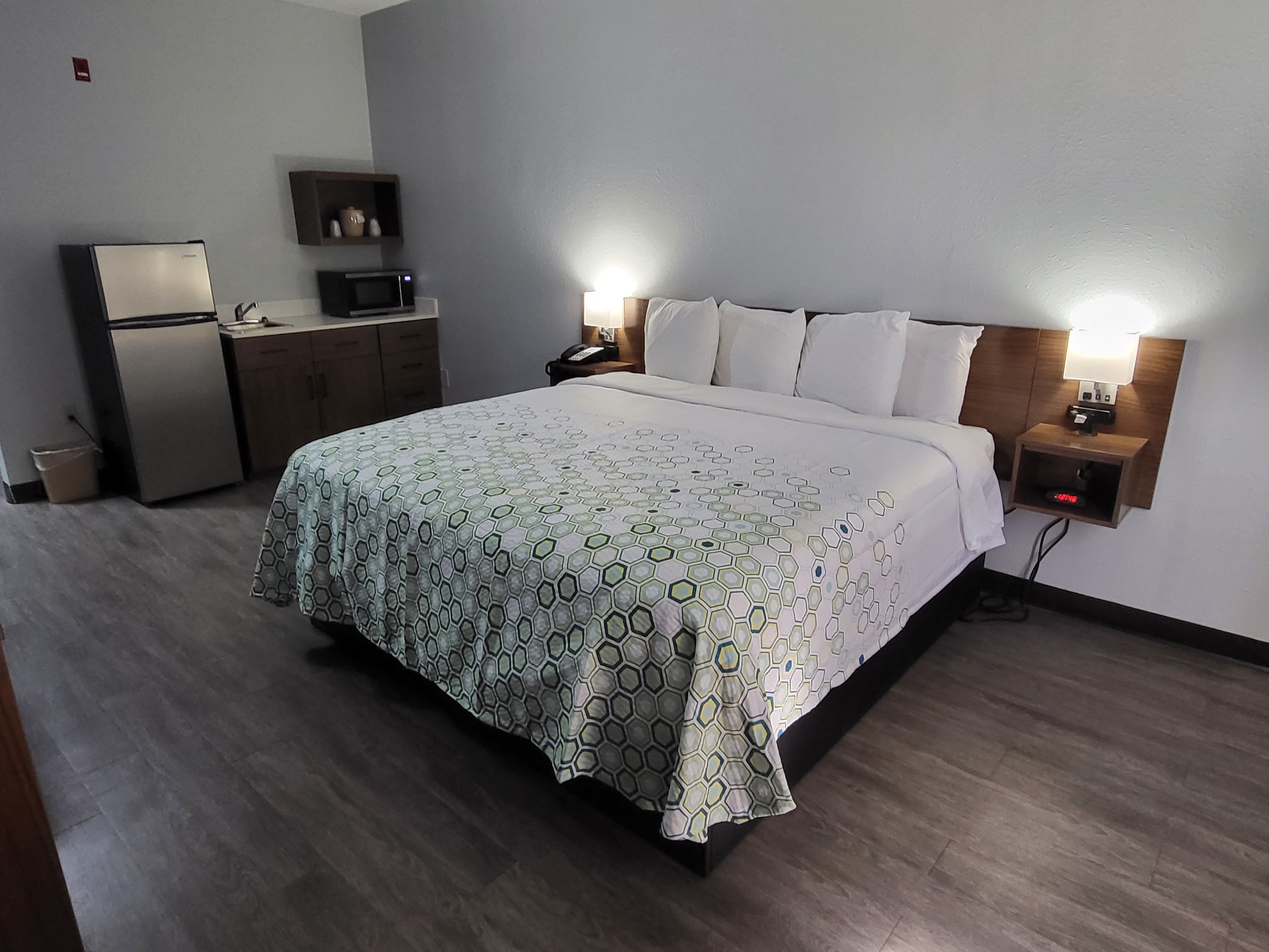 Une chambre d’hôtel équipée d’un lit, de lampes de chevet, d’un bureau avec un micro-ondes et d’un petit réfrigérateur.