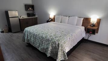 Une chambre d’hôtel équipée d’un lit, de lampes de chevet, d’un bureau avec un micro-ondes et d’un petit réfrigérateur.