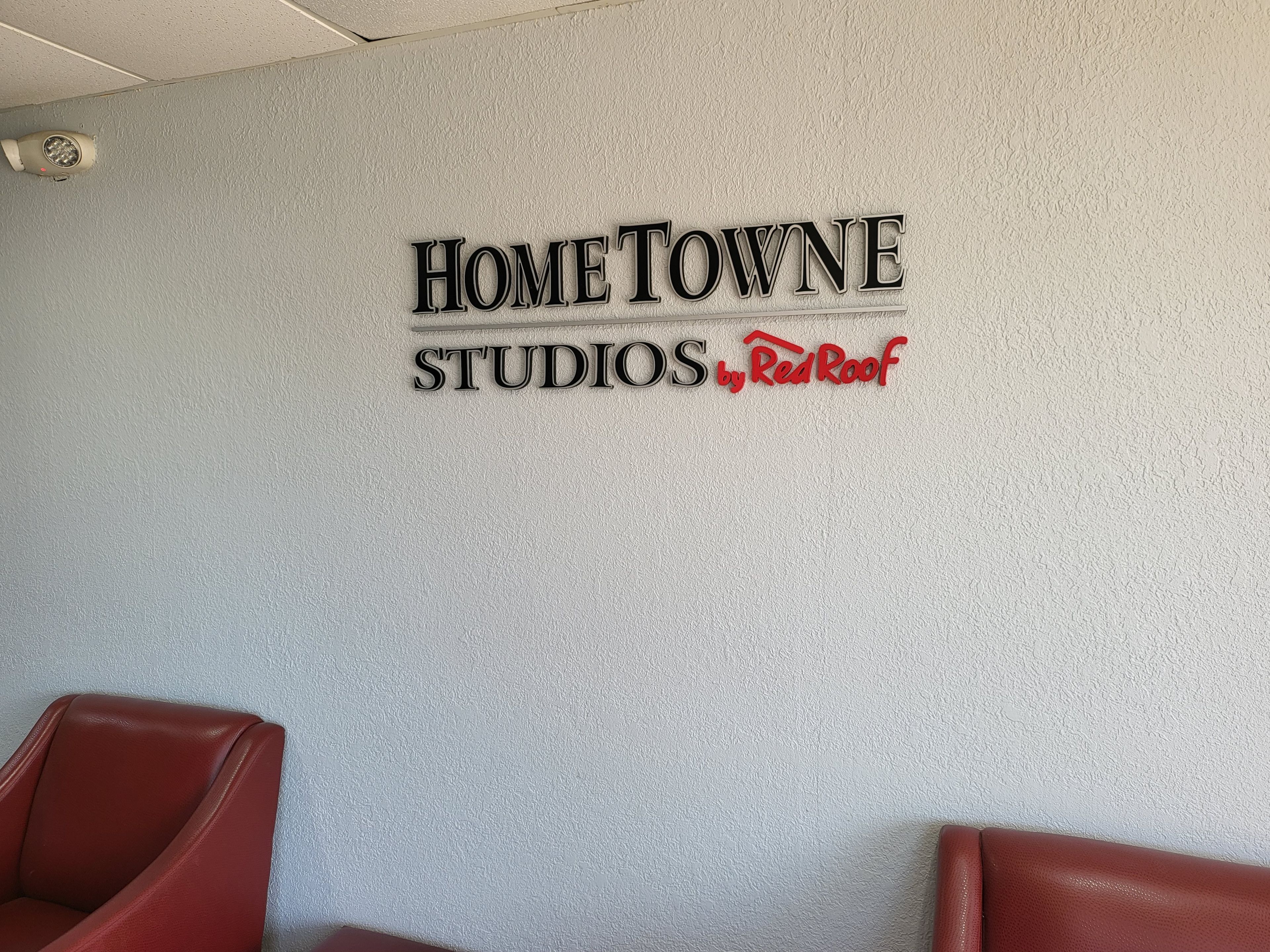 A wall with the text 'HOME TOWNE STUDIOS by Red Roof' and two red chairs.