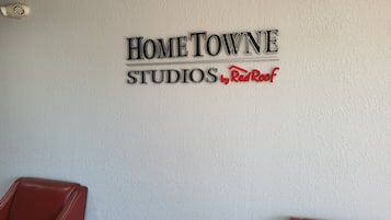 A wall with the text 'HOME TOWNE STUDIOS by Red Roof' and two red chairs.