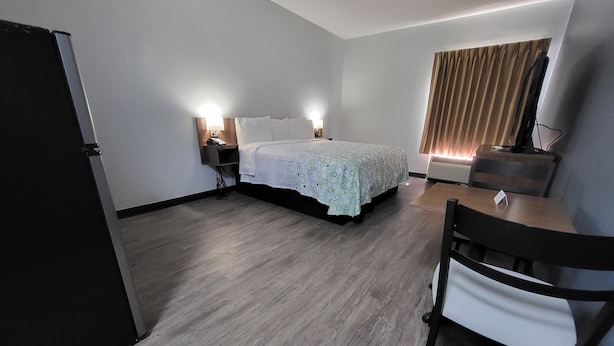 A hotel room with a bed, bedside lamps, a desk, and a chair. - HomeTowne Studios by Red Roof Prattville (Prattville)