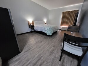 A hotel room with a bed, bedside lamps, a desk, and a chair.