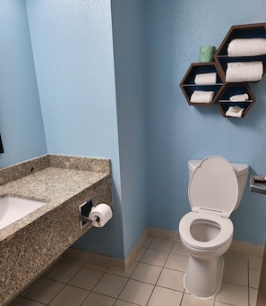 Ein Badezimmer mit Marmorwaschtisch, Toilette und Handtuchhalter mit gefalteten Handtüchern.