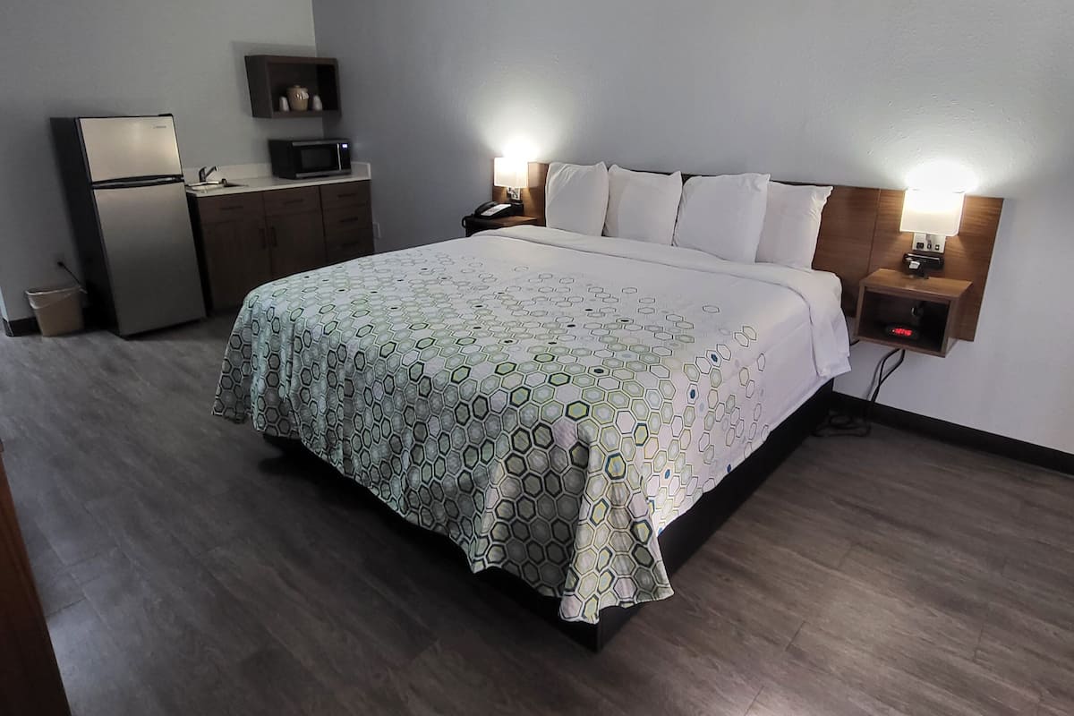 Een hotelkamer met een bed, bedlampjes, een bureau, een magnetron en een kleine koelkast.