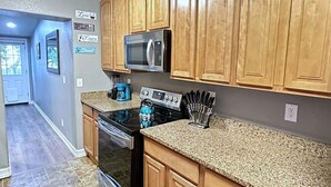 Una cocina con armarios de madera, microondas, estufa y encimera de granito.