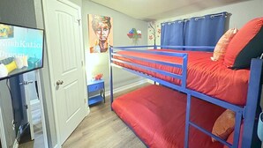 Una habitación con literas, un televisor, una puerta y una pared con un cartel.