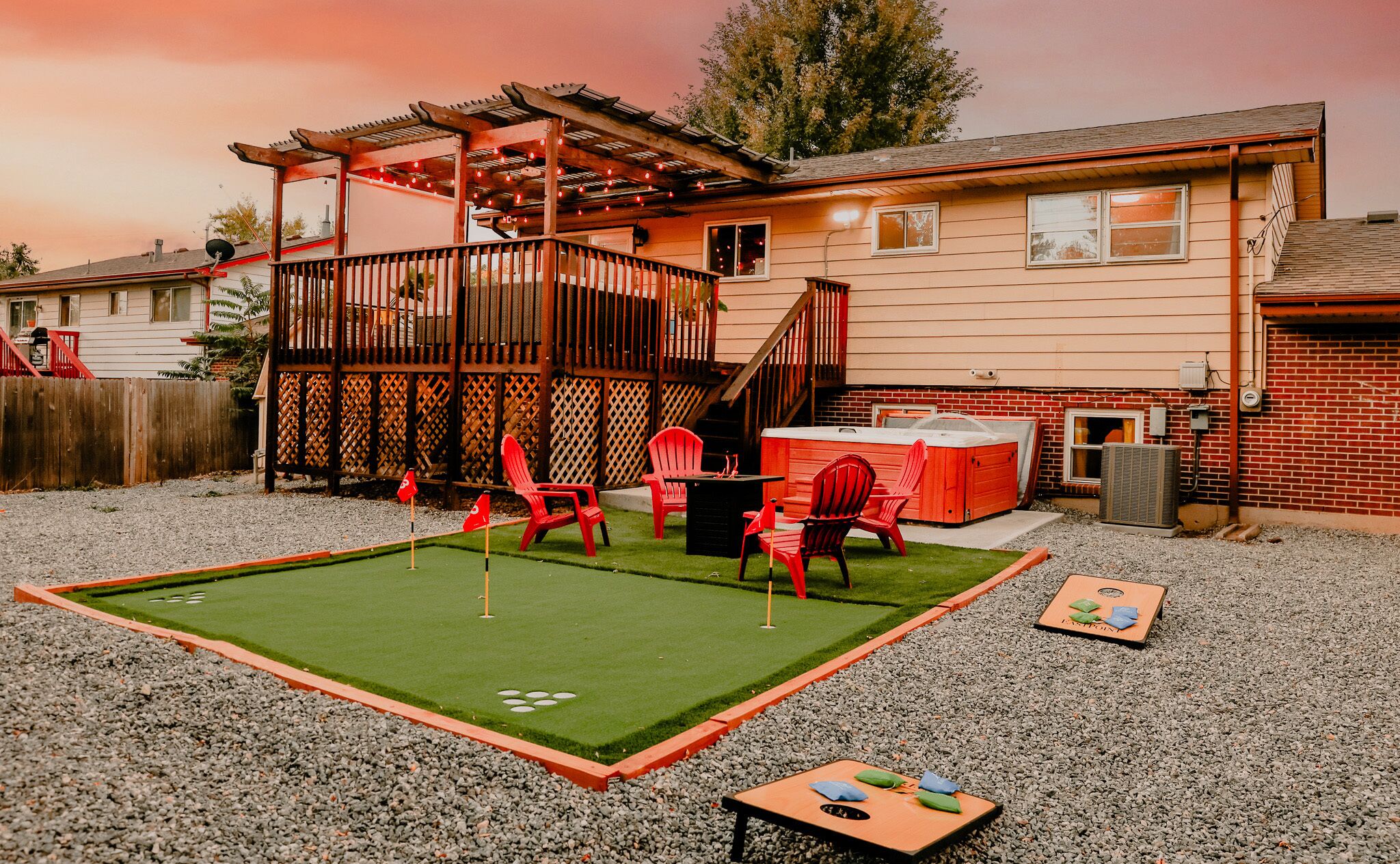 A backyard with a pool table, red chairs, and a hot tub.