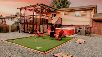 A backyard with a pool table, red chairs, and a hot tub.