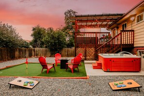 A backyard with a hot tub, a patio table, and red chairs. - HotTub Theater Arcade Gameroom Putt-Putt 420 (Northglenn)