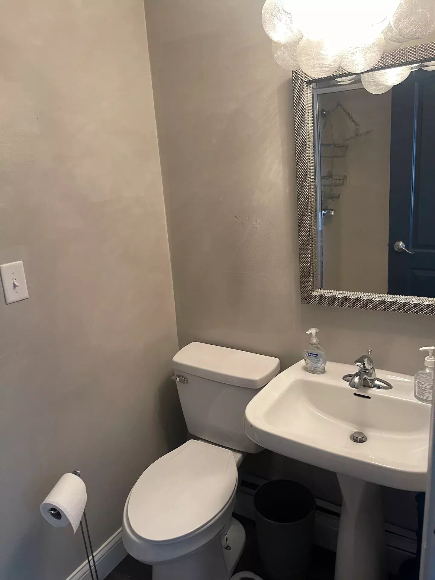 A bathroom with a toilet, sink, and mirror.