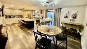 A modern kitchen with a central island, bar seating, and a dining area with a round table and chairs. - The Family and Friends Home
 (New Haven)