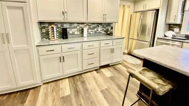 A modern kitchen with white cabinetry, a tiled backsplash, and a stainless steel refrigerator. - The Family and Friends Home
 (New Haven)