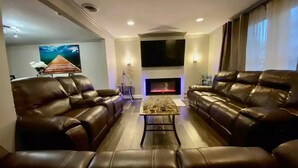 A living room with two leather sofas, a coffee table, a flat-screen TV, and a fireplace. - The Family and Friends Home
 (New Haven)